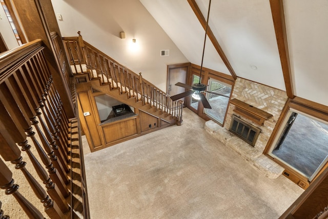 unfurnished living room with high vaulted ceiling, a fireplace, visible vents, beam ceiling, and carpet