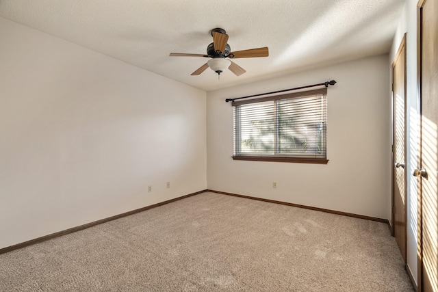 carpeted empty room with a ceiling fan, a textured ceiling, and baseboards