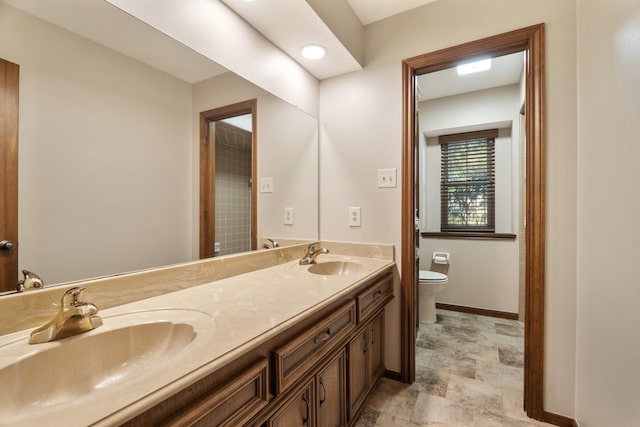 full bathroom featuring baseboards, a sink, toilet, and double vanity