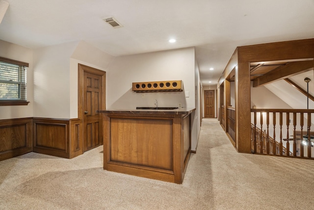 kitchen featuring light carpet, visible vents, brown cabinetry, wainscoting, and recessed lighting