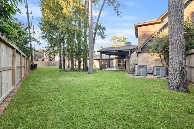 view of yard with a fenced backyard, central AC unit, and a patio