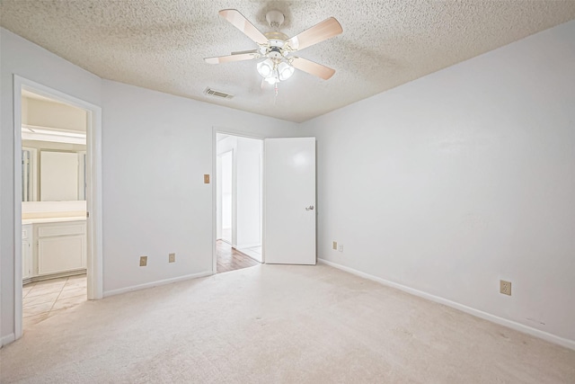 unfurnished bedroom featuring visible vents, light carpet, a textured ceiling, and ensuite bathroom