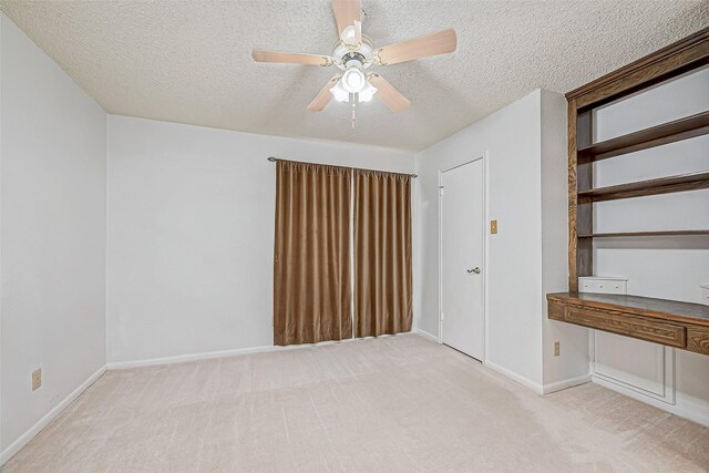 spare room with baseboards, light carpet, a textured ceiling, and a ceiling fan
