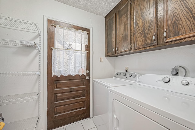 clothes washing area featuring light tile patterned floors, cabinet space, washer and dryer, and a textured ceiling