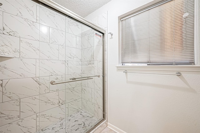 full bathroom with a shower stall, baseboards, and a textured ceiling