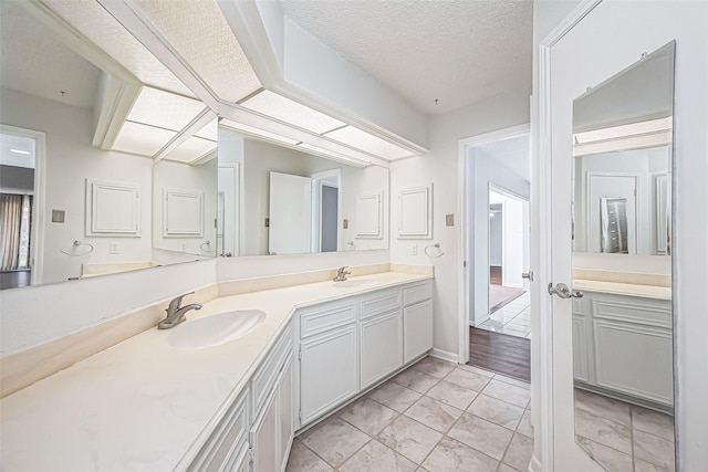 bathroom with double vanity, a textured ceiling, and a sink