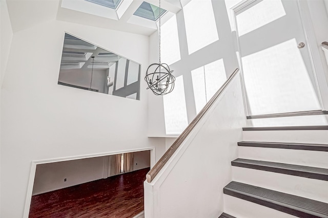 stairs with a skylight and an inviting chandelier