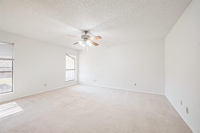 unfurnished room with baseboards, light carpet, a textured ceiling, and a ceiling fan