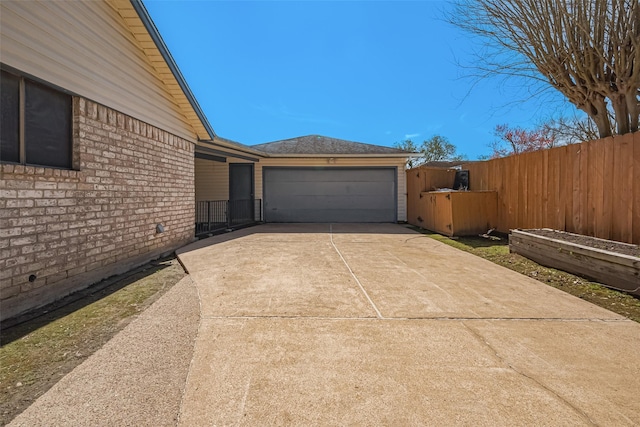 view of home's exterior with a garage, brick siding, driveway, and fence