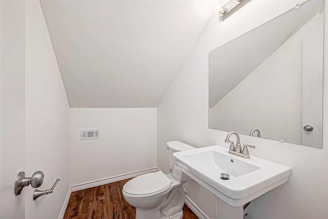 bathroom with wood finished floors, visible vents, a sink, vaulted ceiling, and toilet