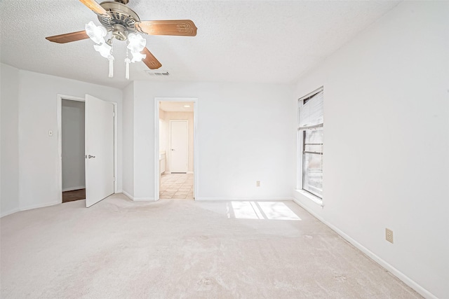 unfurnished room featuring visible vents, light carpet, a ceiling fan, a textured ceiling, and baseboards