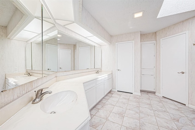 full bathroom featuring double vanity, a textured ceiling, and a sink