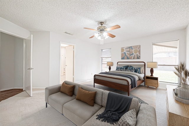 bedroom featuring ceiling fan, multiple windows, visible vents, and a textured ceiling