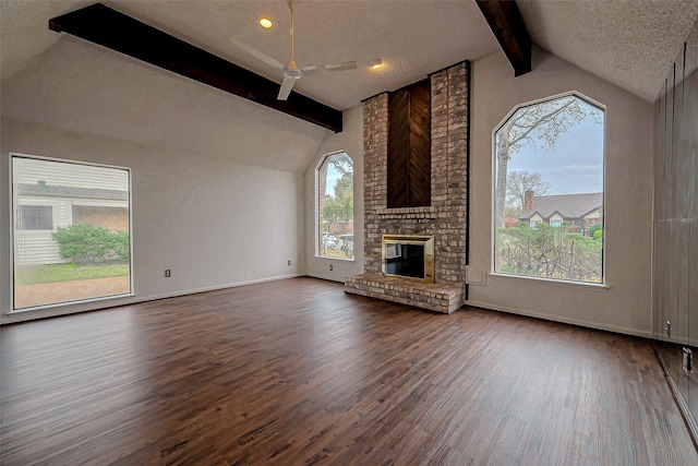 unfurnished living room featuring lofted ceiling with beams, wood finished floors, baseboards, and a textured ceiling