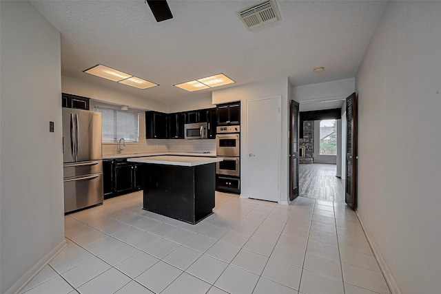 kitchen with visible vents, dark cabinetry, appliances with stainless steel finishes, light countertops, and light tile patterned floors
