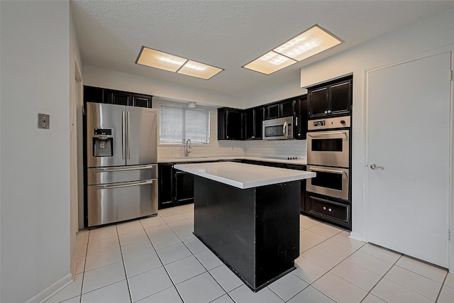 kitchen featuring light tile patterned floors, appliances with stainless steel finishes, dark cabinetry, and light countertops