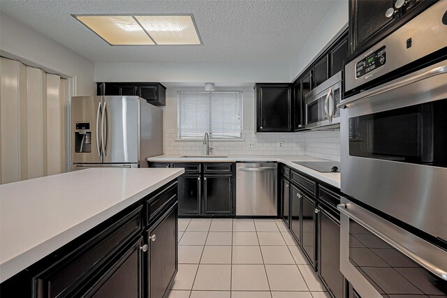 kitchen featuring a sink, stainless steel appliances, light countertops, and dark cabinets