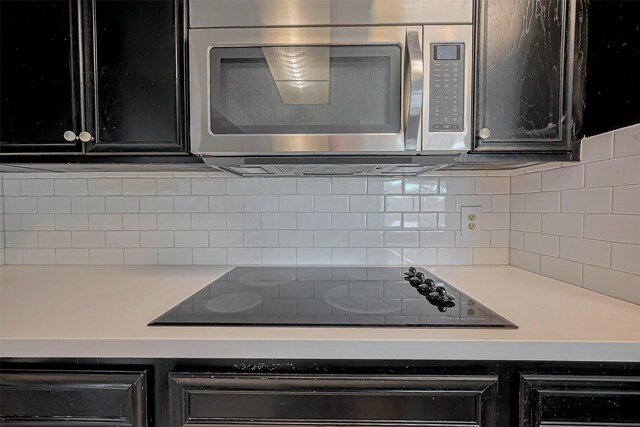 kitchen featuring tasteful backsplash, stainless steel microwave, light countertops, and black electric stovetop