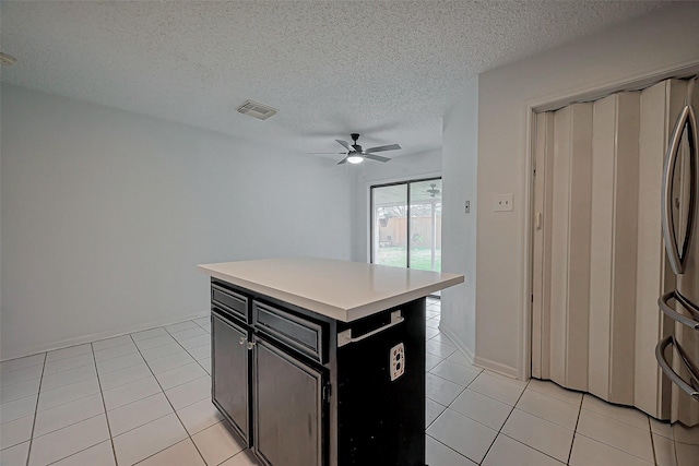 kitchen with light tile patterned floors, dark cabinetry, light countertops, and ceiling fan