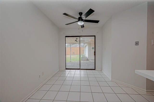 empty room with light tile patterned floors, a textured ceiling, a ceiling fan, and baseboards