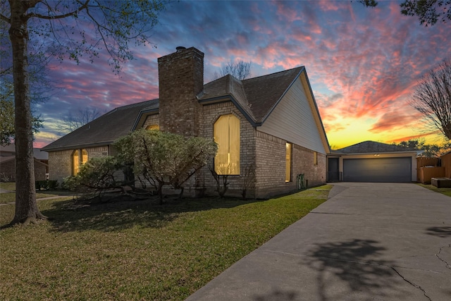 view of front of property featuring brick siding, a chimney, concrete driveway, and a lawn