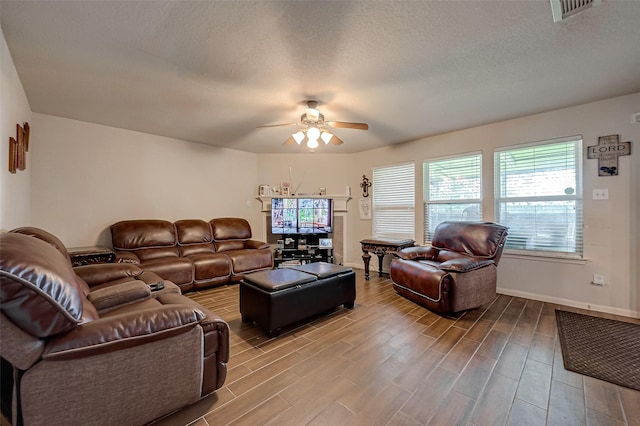 living area with baseboards, visible vents, ceiling fan, wood finished floors, and a textured ceiling