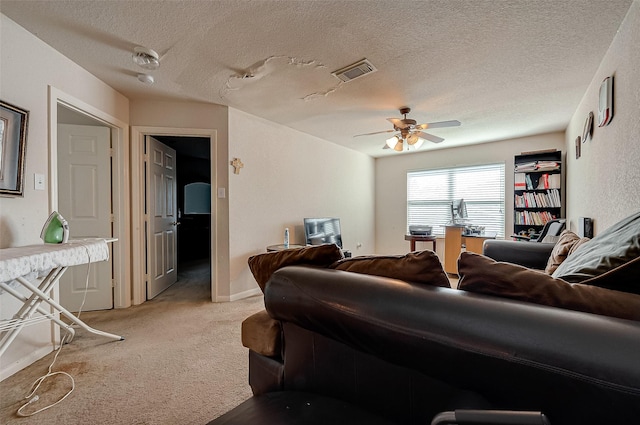 living room with baseboards, visible vents, light colored carpet, ceiling fan, and a textured ceiling