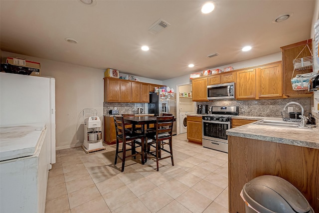 kitchen with light tile patterned floors, visible vents, a sink, stainless steel appliances, and backsplash