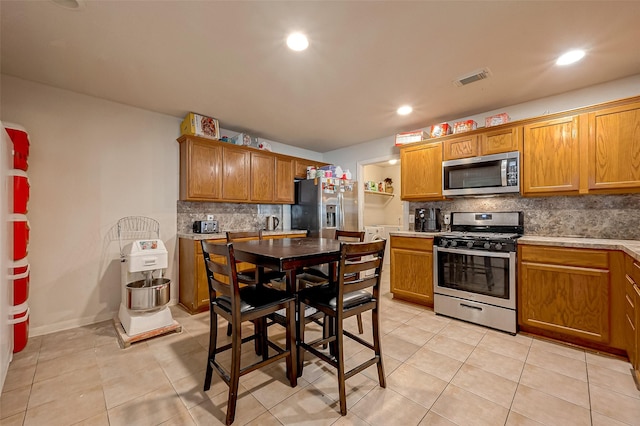 kitchen featuring light tile patterned floors, stainless steel appliances, brown cabinets, and decorative backsplash