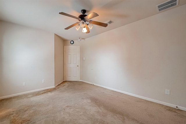 spare room featuring baseboards, a ceiling fan, visible vents, and light colored carpet