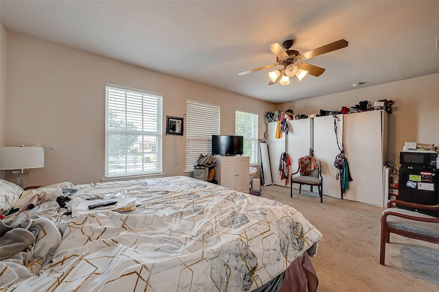 bedroom with light colored carpet, multiple windows, and ceiling fan