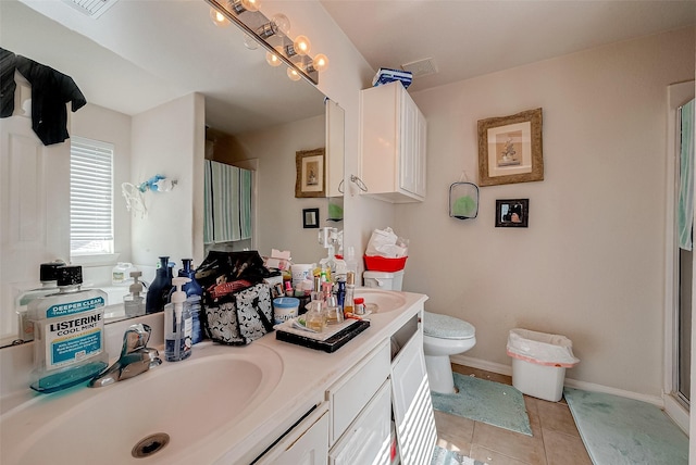 full bathroom featuring double vanity, baseboards, toilet, tile patterned flooring, and a sink