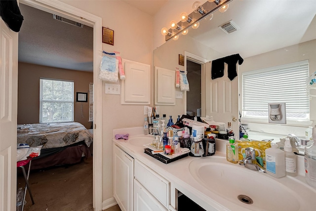 ensuite bathroom featuring connected bathroom, visible vents, and a sink