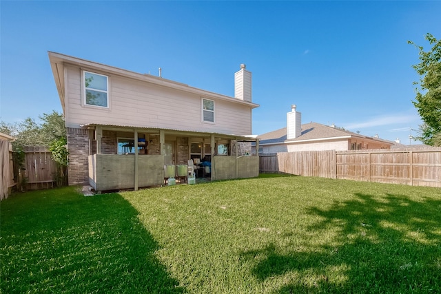 rear view of property with a fenced backyard, a lawn, and brick siding