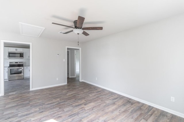 spare room with ceiling fan, wood finished floors, visible vents, baseboards, and attic access