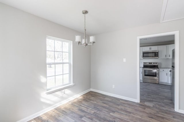 unfurnished dining area featuring dark wood-style floors, a chandelier, and baseboards