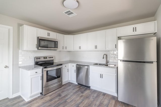 kitchen featuring stainless steel appliances, a sink, visible vents, white cabinetry, and dark wood finished floors