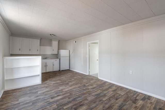 kitchen featuring dark wood-style flooring, crown molding, light countertops, freestanding refrigerator, and white cabinets