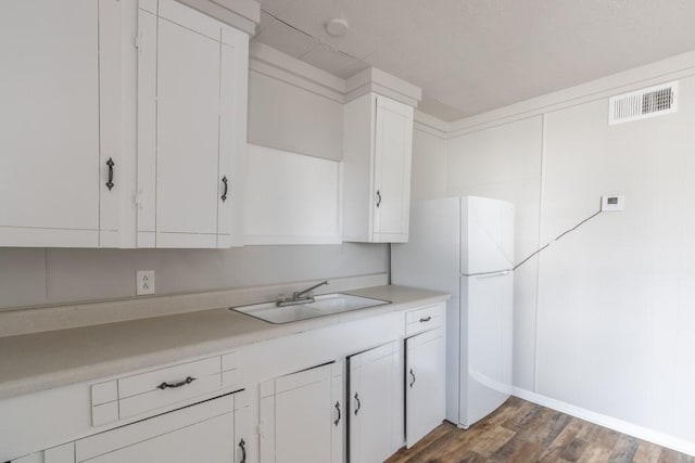 kitchen with visible vents, dark wood-style flooring, light countertops, white cabinetry, and a sink