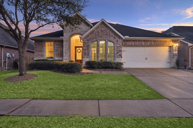 view of front facade with driveway, a garage, a lawn, and brick siding