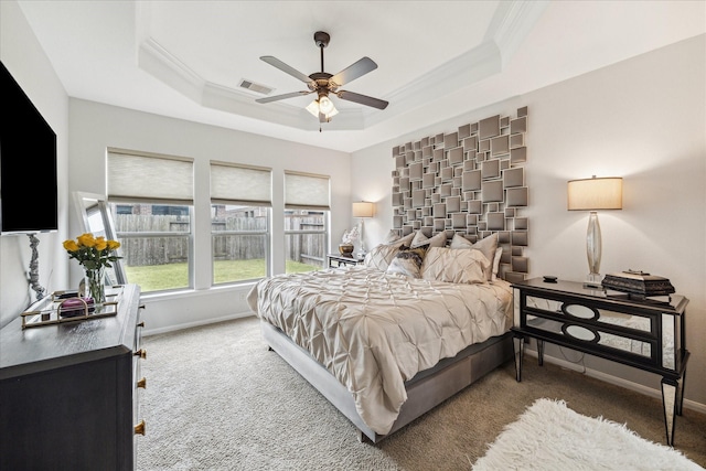 bedroom featuring ornamental molding, a tray ceiling, visible vents, and baseboards