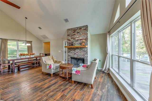 living room with a brick fireplace, visible vents, a wealth of natural light, and dark wood-style flooring