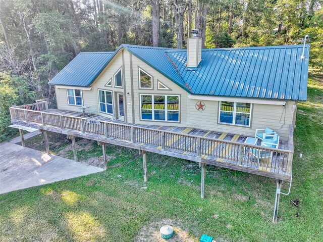 480 Caney Creek Dr, Livingston, TX 77351 - rear view of house featuring a chimney, a deck, metal roof, and a yard
