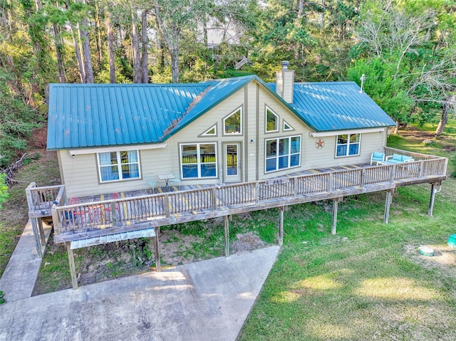 exterior space featuring a deck, a front yard, metal roof, and a chimney