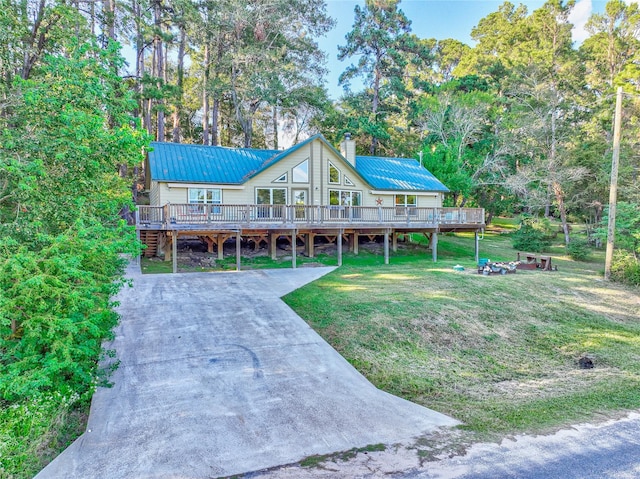 rustic home with metal roof, concrete driveway, a front lawn, and a chimney