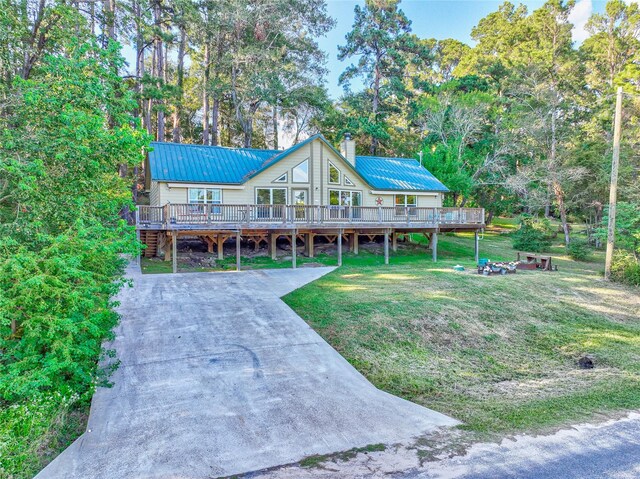 480 Caney Creek Dr, Livingston, TX 77351 - view of front of home with a chimney, a deck, metal roof, and a front lawn