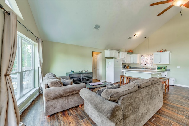 living area featuring ceiling fan, high vaulted ceiling, visible vents, baseboards, and dark wood-style floors