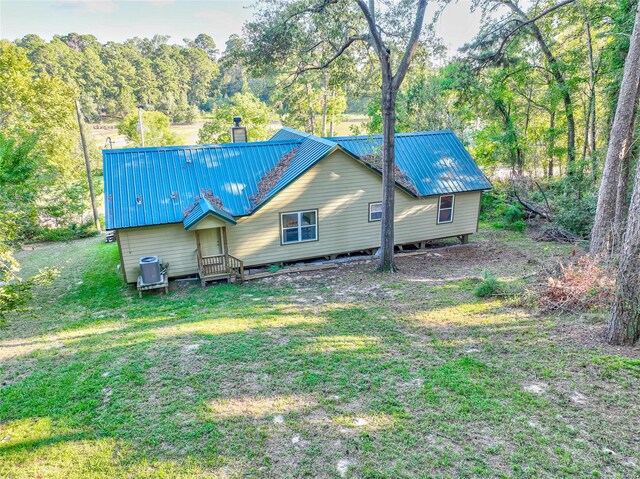 480 Caney Creek Dr, Livingston, TX 77351 - back of house with a yard, metal roof, and a chimney