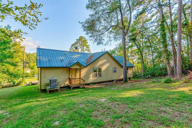 480 Caney Creek Dr, Livingston, TX 77351 - back of property with central AC, a yard, metal roof, and a chimney