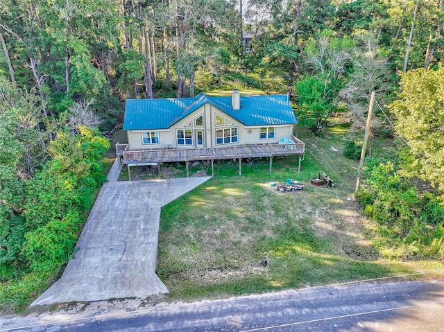 view of front facade featuring a forest view, a chimney, a front lawn, and metal roof